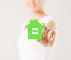 Manos de la mujer que sostienen la casa verde | Foto de stock