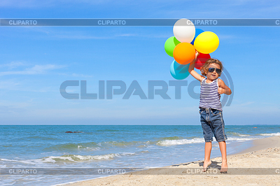 El niño pequeño con los globos coloca en la playa | Foto de alta resolución |ID 6194235